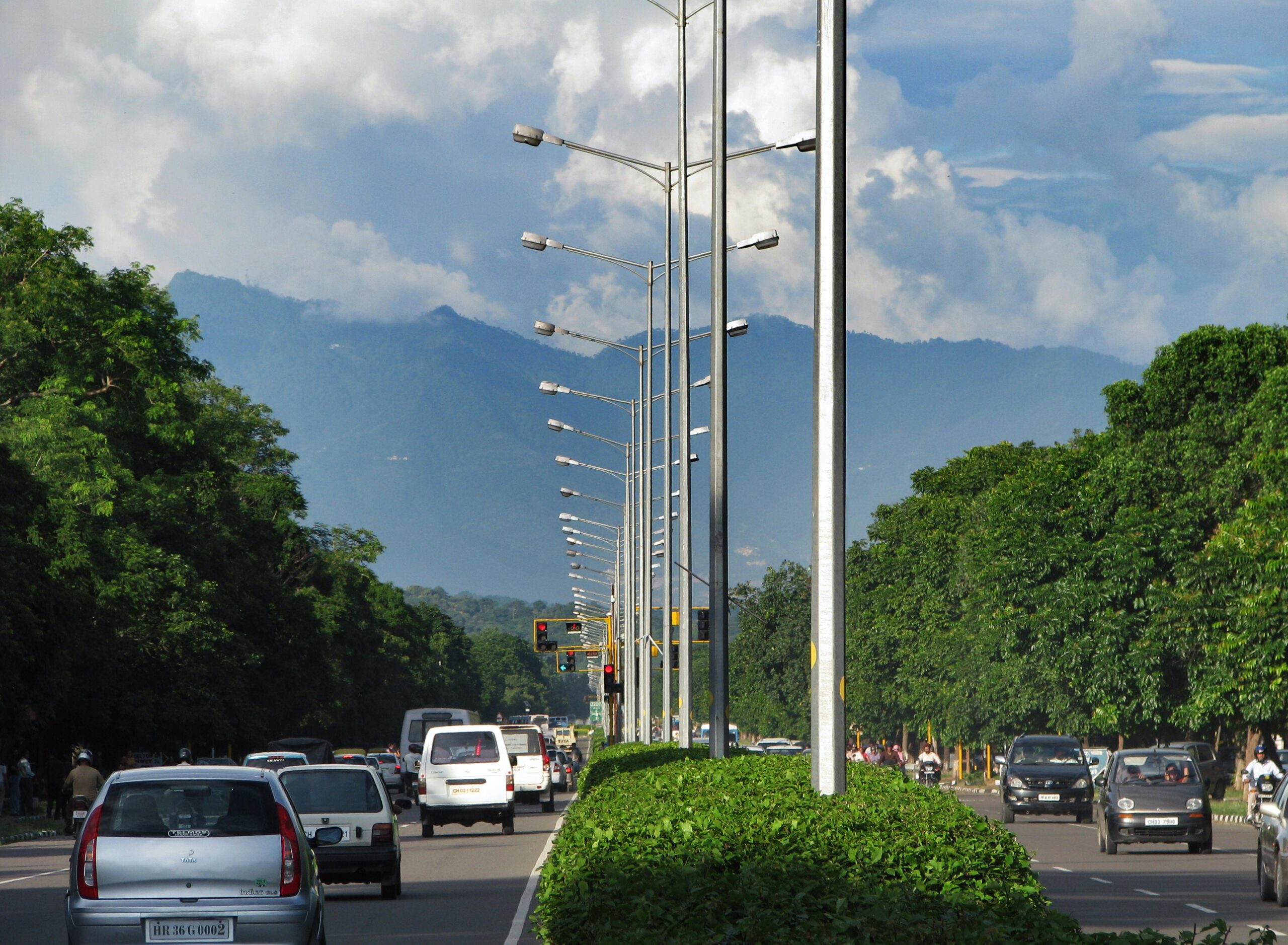Traffic flows on a tree-lined road with stunning mountain backdrop.